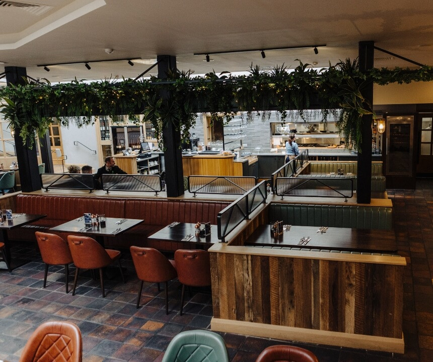 A beautiful open restaurant with plenty of space and seating area with a view into the kitchen
