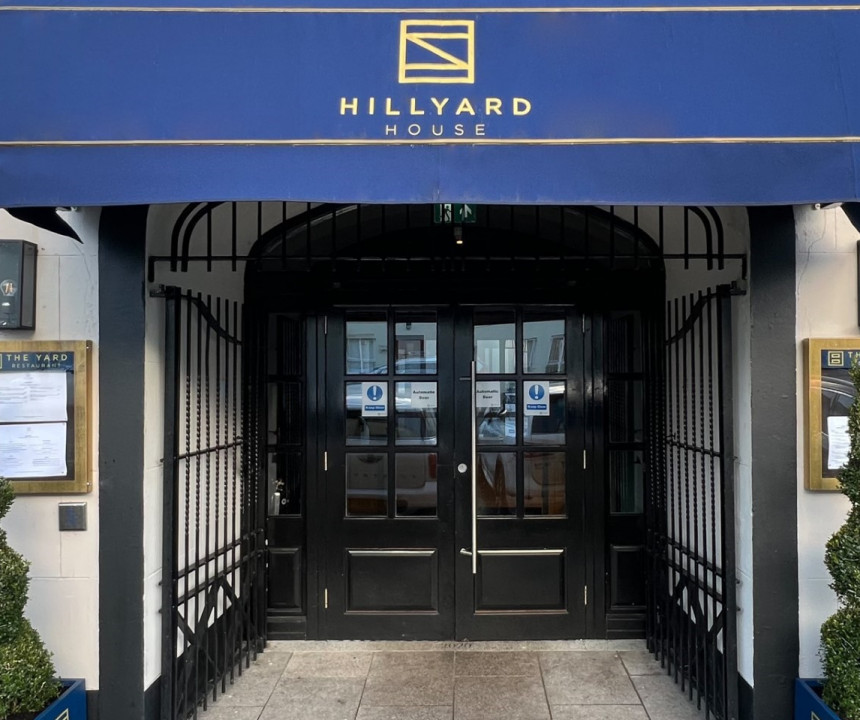 Black exterior double doorway with a navy canopy showcasing Hillyard House Hotels logo