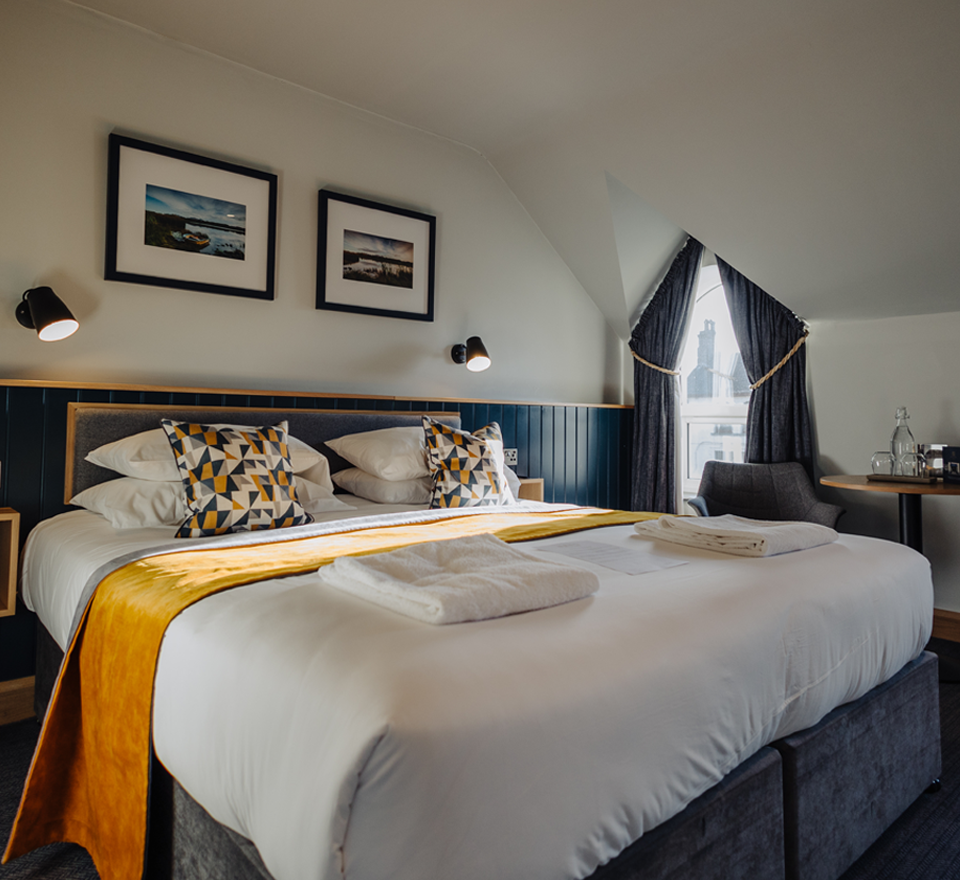 Hotel room with clean, fresh white sheets and gold throws