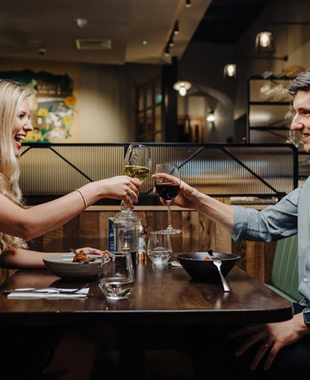 A couple cheering wine glasses over a dinner in a restaurant